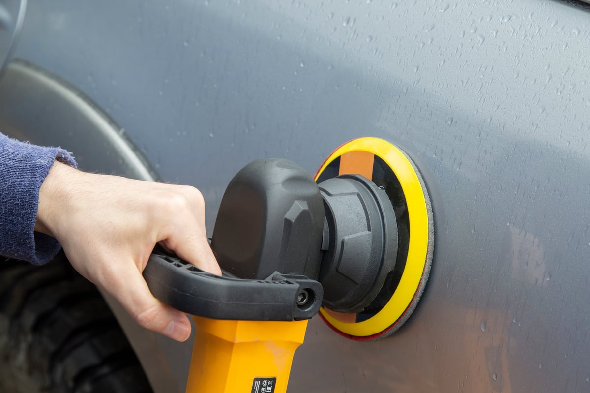 Polishing the car body with a grinder after bodywork for a clean finish